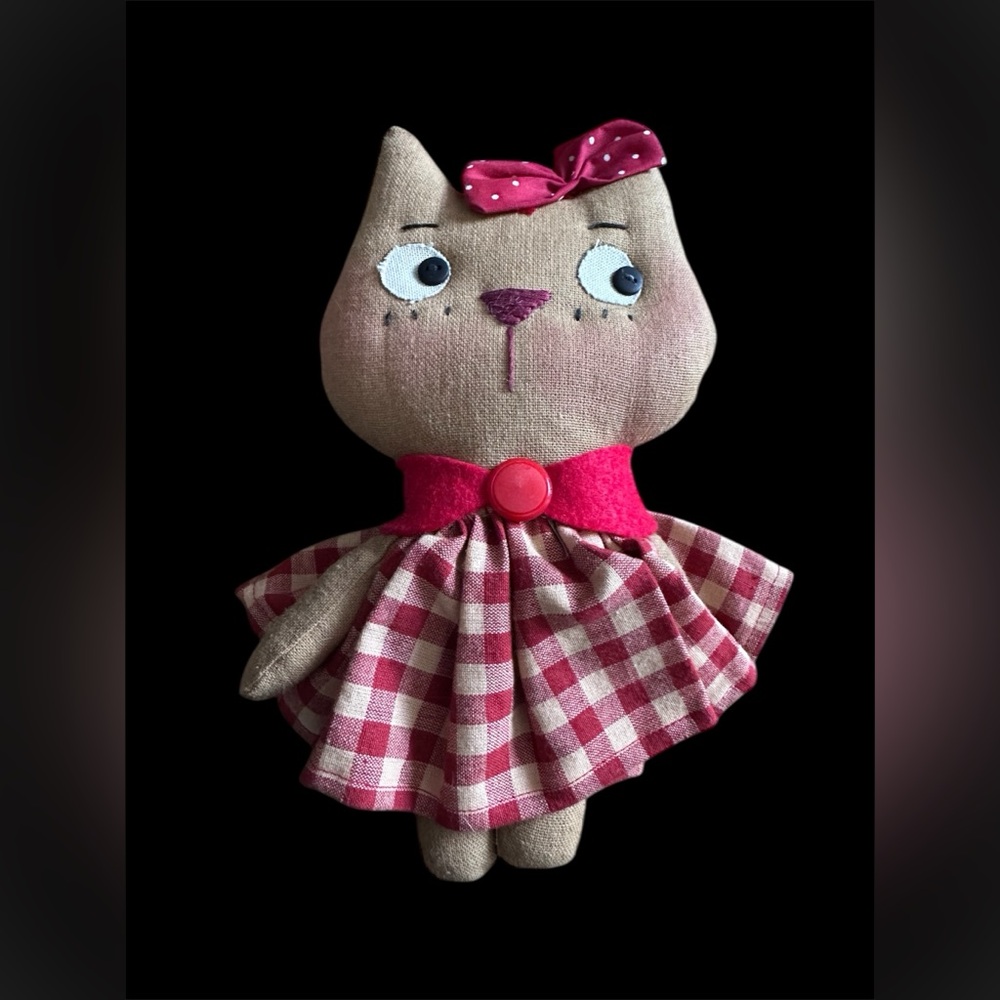 Handmade cloth cat doll in a red and white plaid dress.